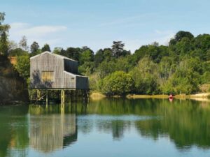 wooden boathouse across green blue lagoon buckland park lake surrey